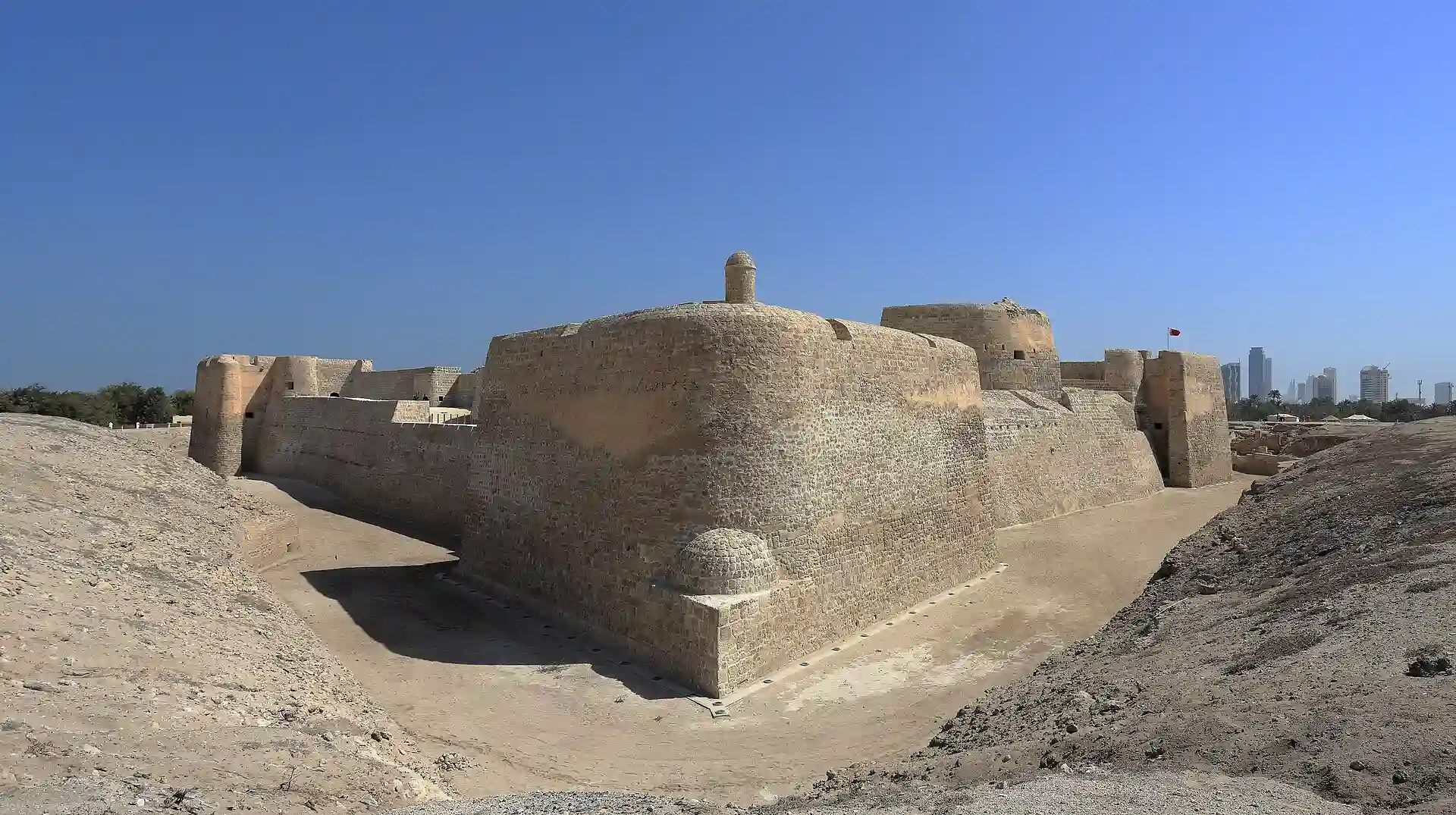 Travel guide to Bahrain featuring the historic Qal'at al-Bahrain fort against the blue sky