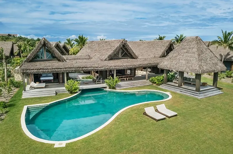 Travel guide to Fiji featuring a pristine white sand island beach with overwater bungalows and turquoise South Pacific waters