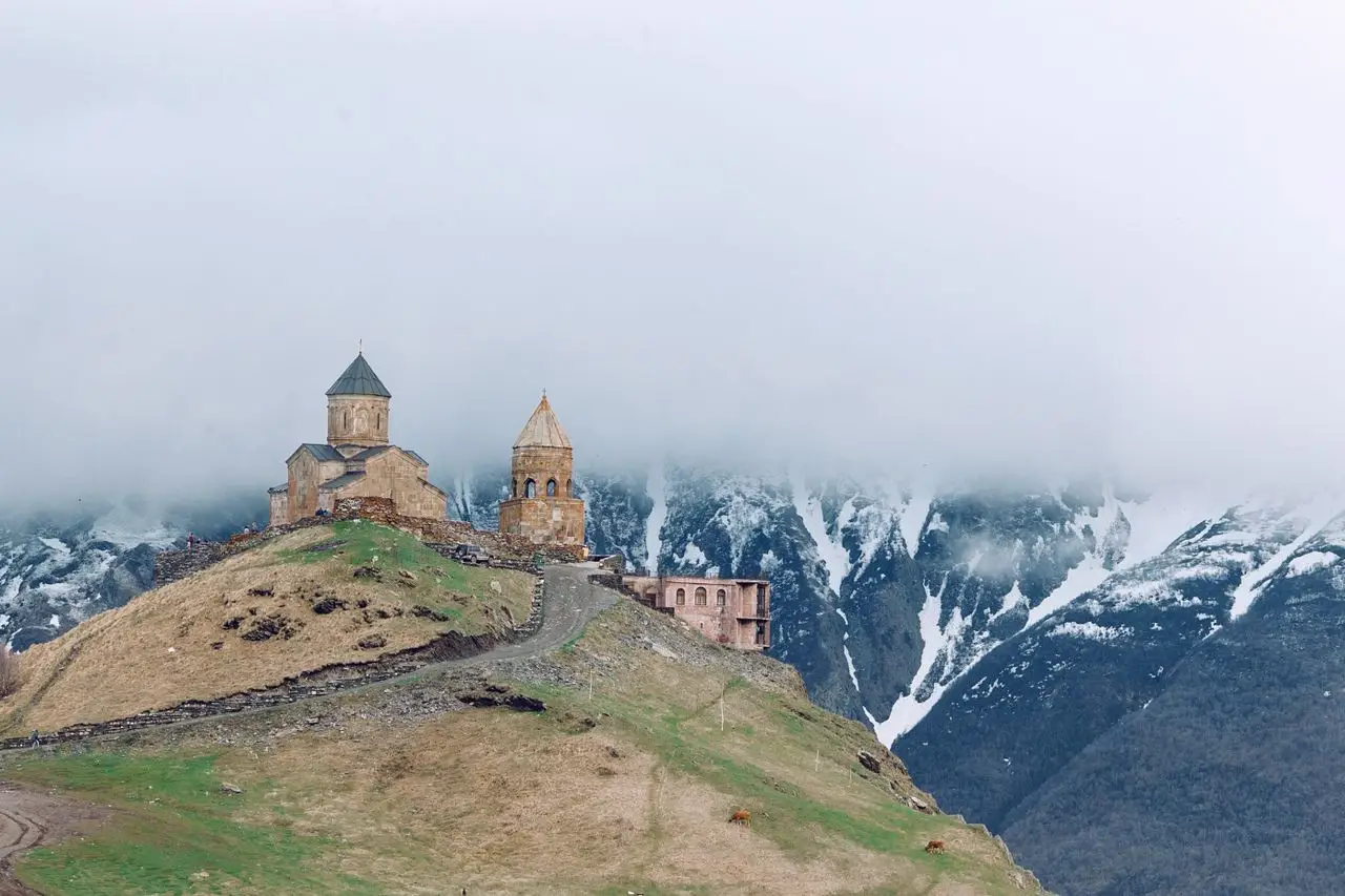 Travel guide to Georgia featuring the iconic Gergeti Trinity Church perched high in the Caucasus mountains near Mount Kazbek