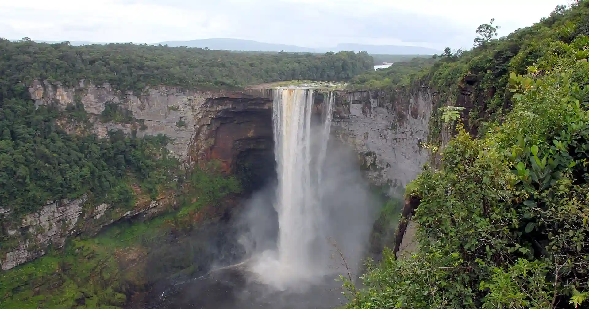 Travel guide to Guyana featuring Kaieteur Falls cascading over a sheer sandstone cliff surrounded by lush Amazonian rainforest