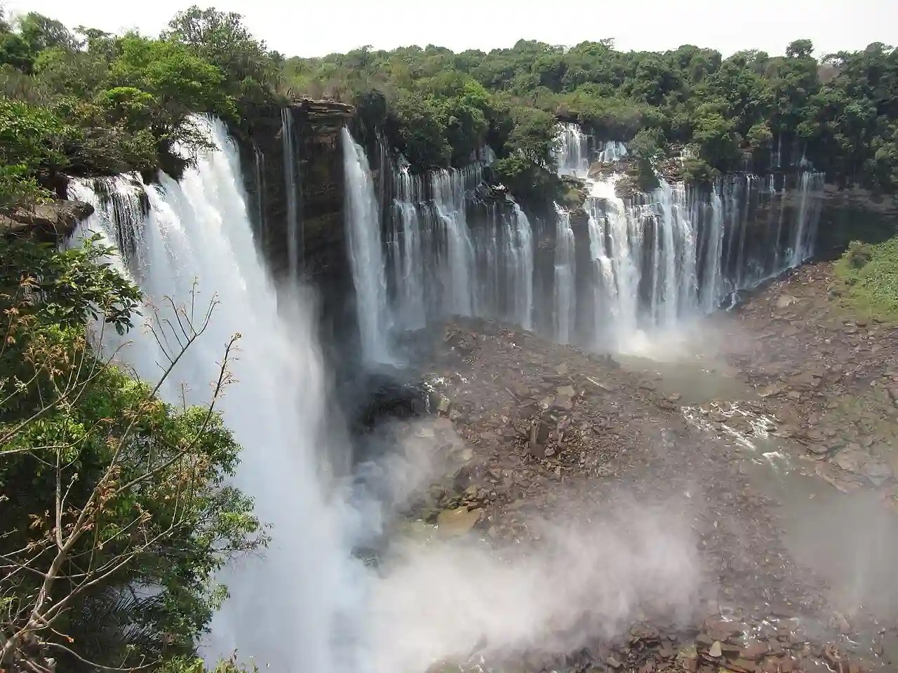 Travel guide to Angola featuring the panoramic horseshoe shape of Kalandula Falls surrounded by lush green tropical wilderness