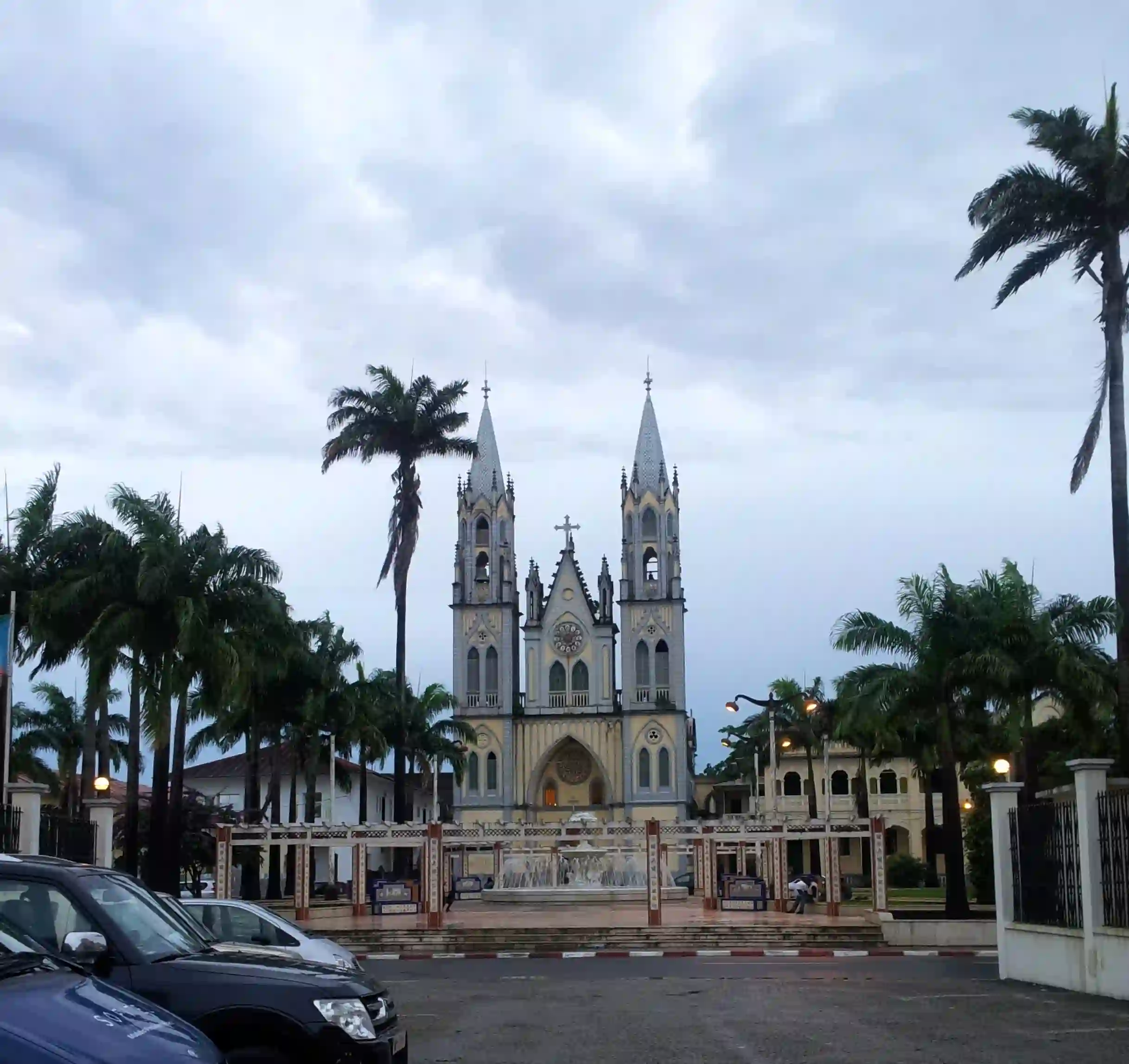 Travel guide to Equatorial Guinea featuring the colorful colonial Cathedral of Santa Isabel set against lush tropical palm trees in Malabo