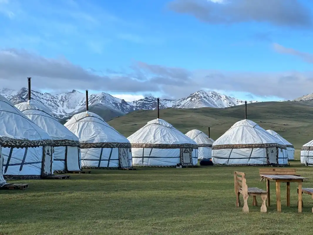 Travel guide to Kyrgyzstan featuring traditional nomadic yurts along Song-Kul Lake surrounded by mountain pastures